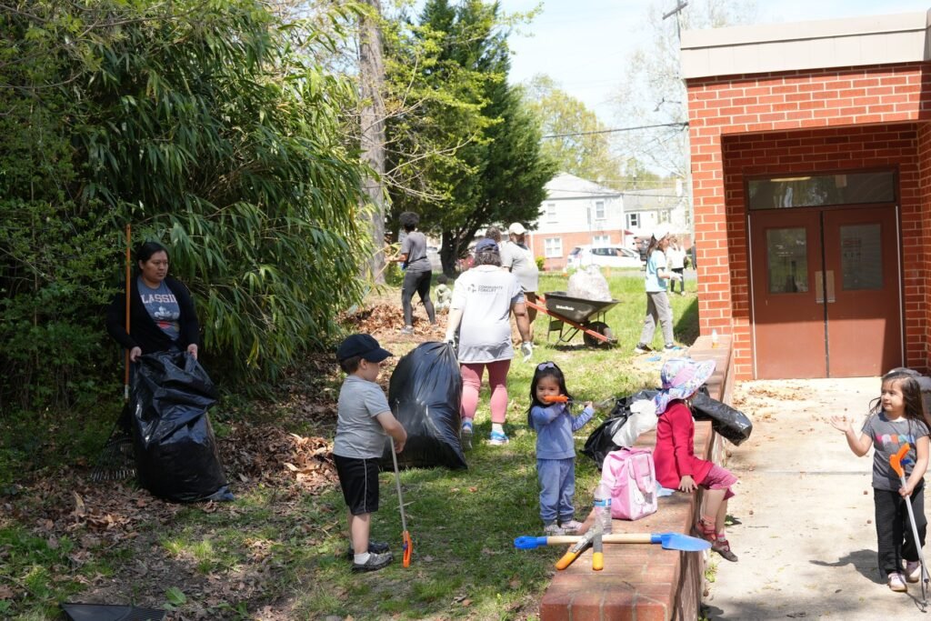 Young students raking leaves and filling bags on a Wildcat Way workday